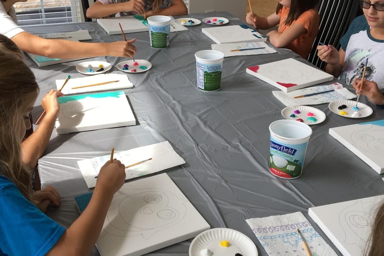 Kids painting on canvases at a birthday paint party