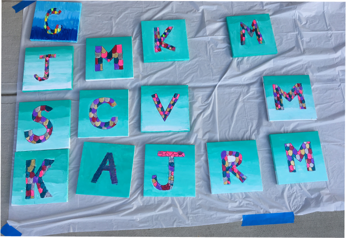 Mosaic letter canvas paintings by kids drying on a tarp