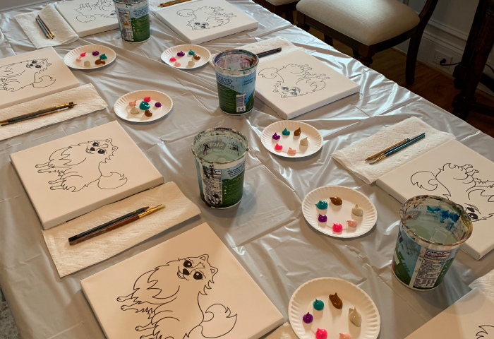 Paint party table setup with pre-sketched puppy canvases and paint palettes