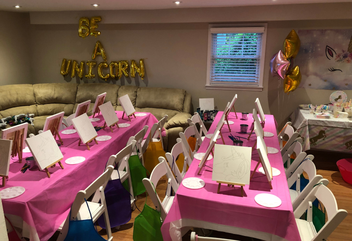 Unicorn themed paint party with easels, pink tables, and Be A Unicorn balloon letters